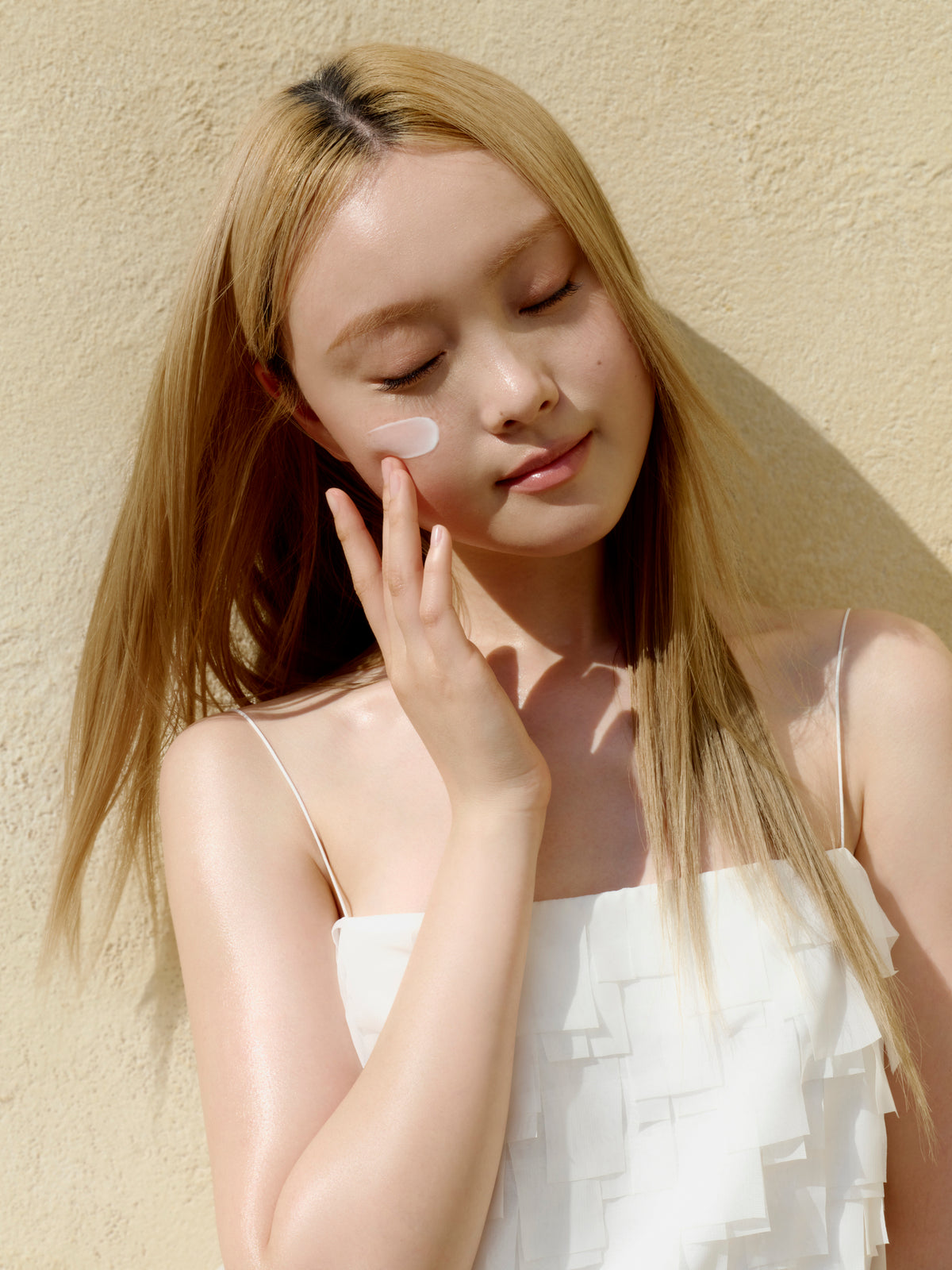 a woman with eyes closed and a cream on her face