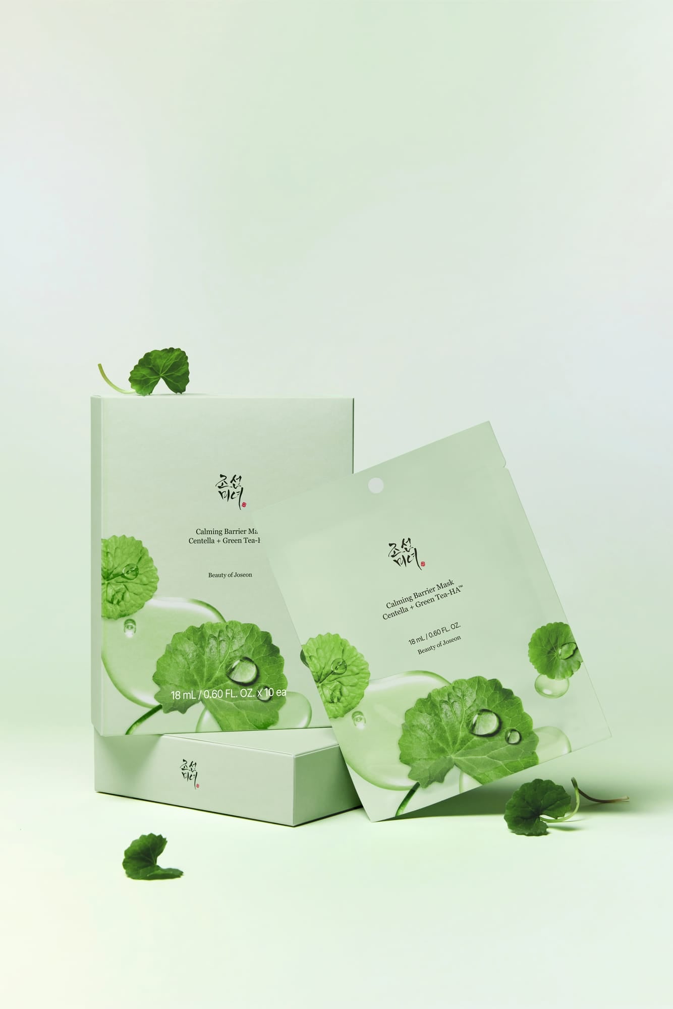 A set of botanical facial cleansing pads in a light mint green packaging, featuring green leaf illustrations and water droplets, arranged on a matching light green background with a few scattered leaf props.