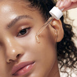 a woman applying a dropper on her face