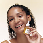 a woman smiling holding a small bottle of liquid