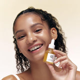 a woman smiling holding a small bottle of liquid