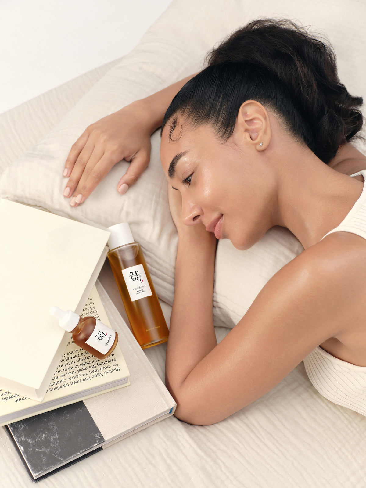 a woman lying on a bed with a book and bottles of essential oils